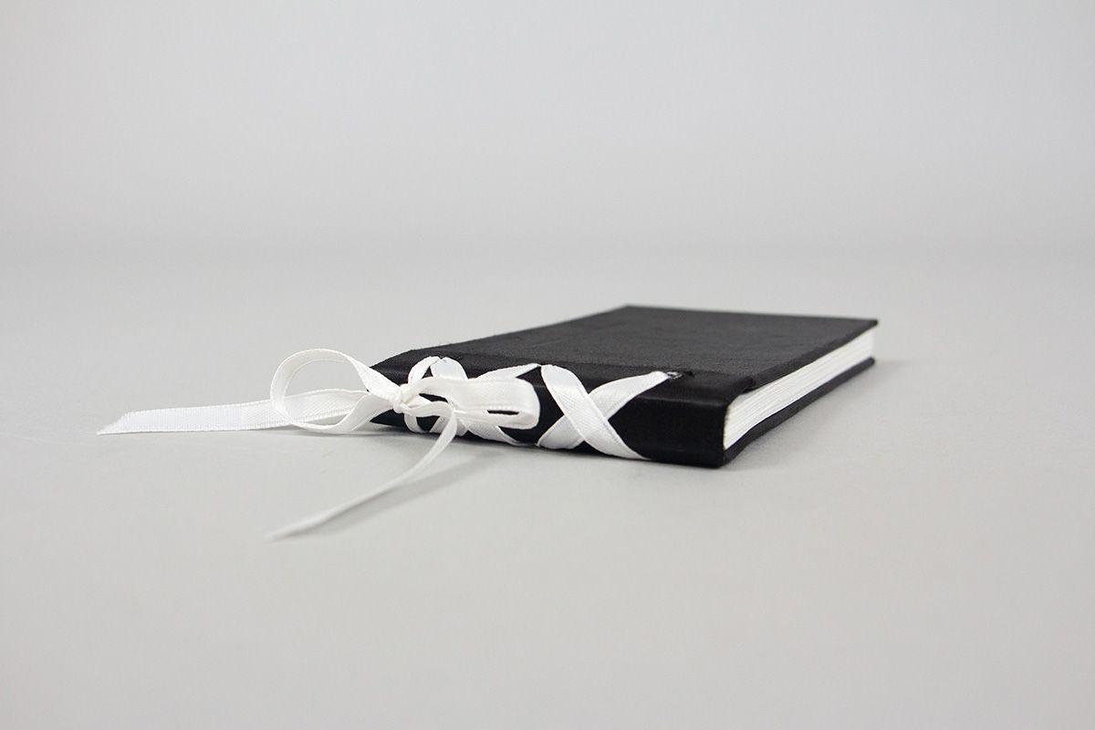 A black satin book with a white satin ribbon binding