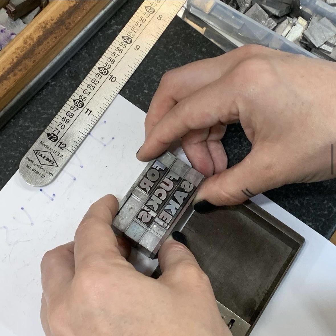 Hands aligning metal type